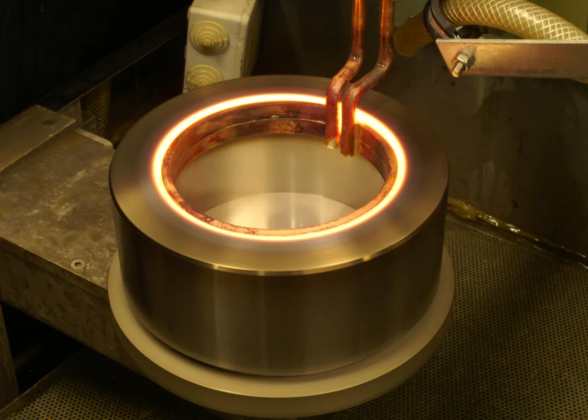 Induction hardening of a steel ring: the edge glows orange inside the copper inductor